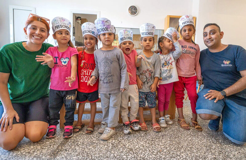 DEICHMANN Stiftung | Roma-Integration Griechenland – frühkindliche Bildung – Vorschulkinder bereiten sich auf Einschulung vor Deichmann Stiftung | Roma-Integration Griechenland – frühkindliche Bildung – Vorschulkinder mit gebastelten Hüten mit Preschool-Beschriftung